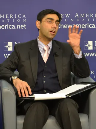 Moeed Yusuf speaking at a panel discussion, seated with papers in hand.